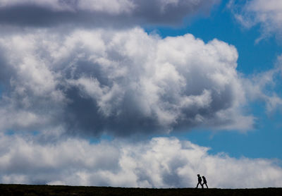 People standing on land against blue sky