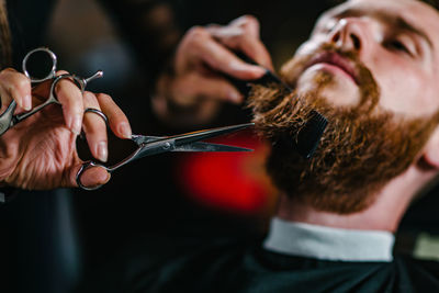 Close-up of woman cutting man beard
