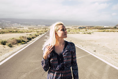 Thoughtful young woman standing on road at desert
