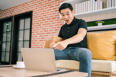 Full length of man using mobile phone while sitting on table