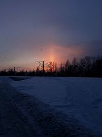 Scenic view of snow covered field against sky at sunset