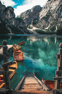 Boats moored in lake against rocky mountains