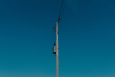 Low angle view of crane against clear blue sky