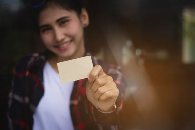 Portrait of smiling young woman holding blank business card