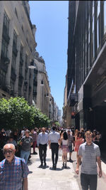 People walking on street amidst buildings in city