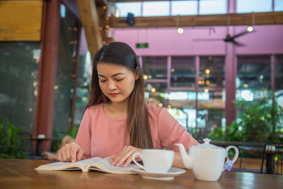 Young woman using mobile phone while sitting at cafe