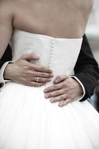 Midsection of bride holding wedding dress