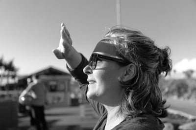 Caucasican adult woman  looking at the sun and covering his hand causing shadows on his face.