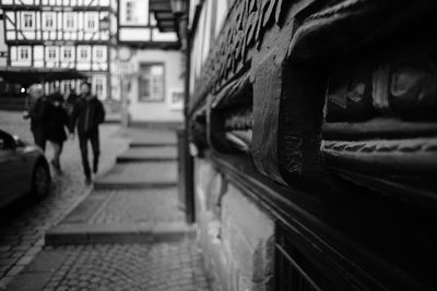 Rear view of people walking on alley amidst buildings in city