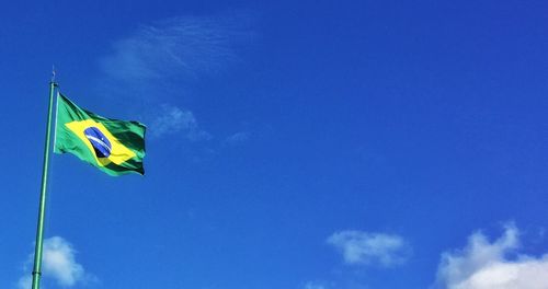 Low angle view of flag flags against blue sky