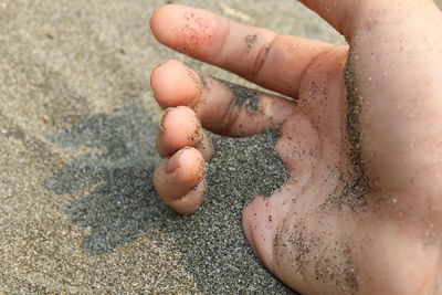 Close-up of hand in sand at beach