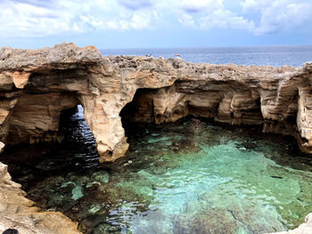 Rock formations in sea against sky