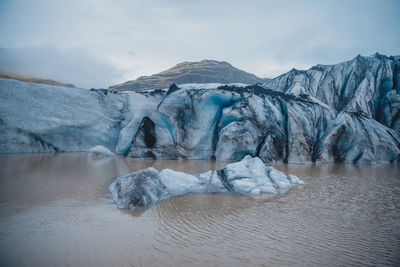 Iceberg in lake against snowcapped mountains