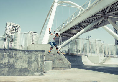 Low section of man skateboarding on skateboard against sky