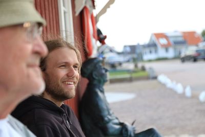 Father and son talking while sitting against wall at yard