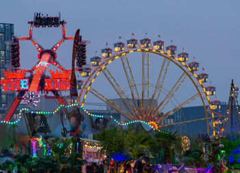 People in amusement park ride against sky