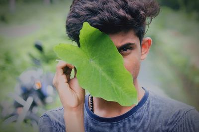 Portrait of teenage boy holding leaf