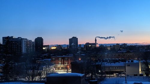 Illuminated buildings in city against sky during sunset