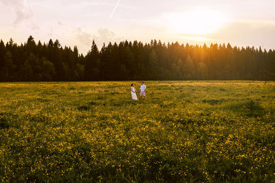 Couple holding hands while standing amidst plants against sky