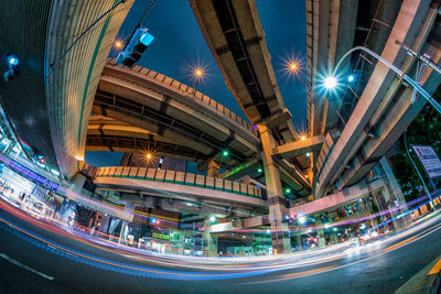 Illuminated light trails on street amidst buildings in city at night