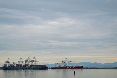 Cranes at commercial dock against sky