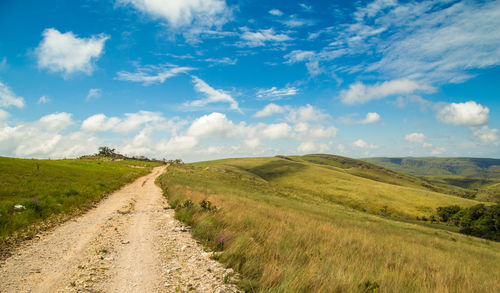 Road amidst field against sky