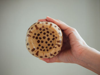 Close-up of hand holding ice cream over white background