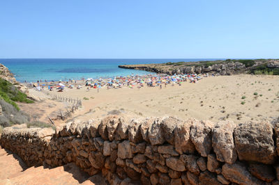 People at beach against clear sky