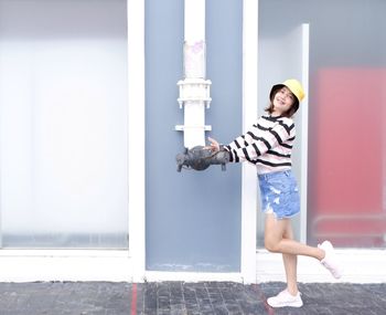 Side view of young woman standing against wall