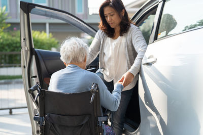 Asian senior woman patient sitting on wheelchair prepare get to her car