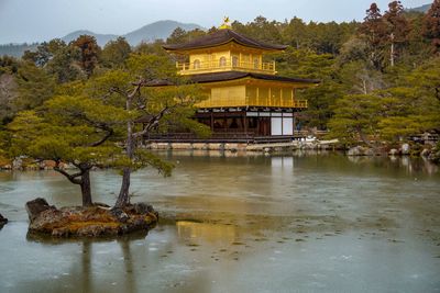 Built structure by lake against trees and building