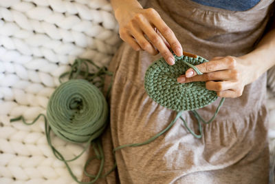 Midsection of woman crocheting at home