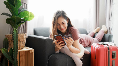 Smiling woman online shopping though mobile phone at home