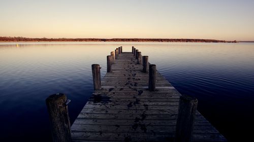 Wooden pier on lake against sky during sunset