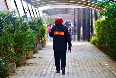 Full length rear view of man walking on cobblestone