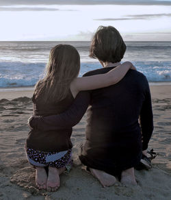 Rear view of women sitting on beach