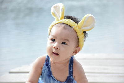 Close-up of cute baby girl wearing headband on pier in lake