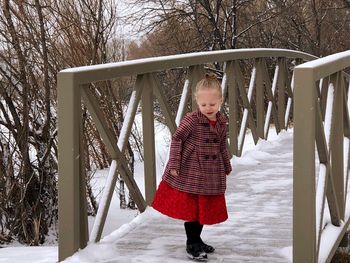 Cute girl standing on snowy footbridge