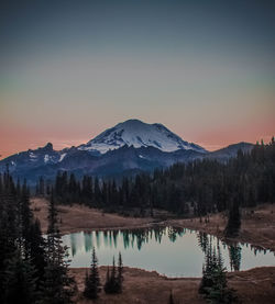 Scenic view of lake by mountains against sky during sunset