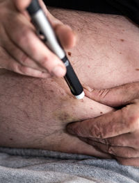 Midsection of man injecting insulin in abdomen