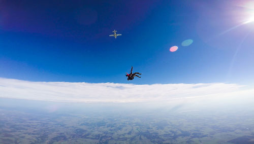 People tandem skydiving against blue sky