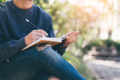 Midsection of man sitting with book