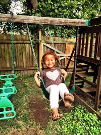 Full length of happy girl enjoying swing at yard