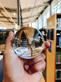 Cropped hand of person holding crystal ball at library