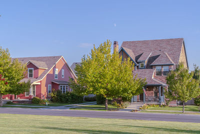 Houses and trees by road against blue sky