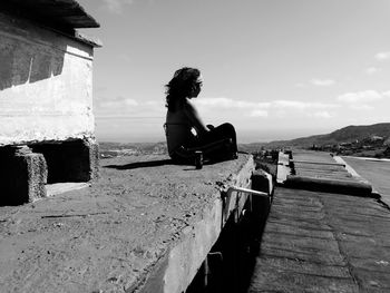 Side view of a man sitting in front of sea