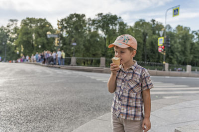 Boy eating ice cream on sidewalk