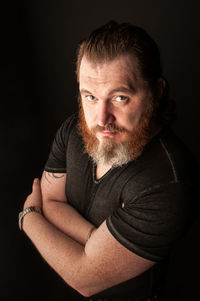 Portrait of man sitting against black background