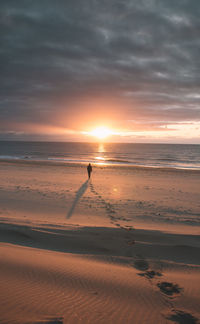 Silhouette man standing on beach against sky during sunset