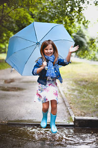 Full length of a smiling woman standing on wet rainy day